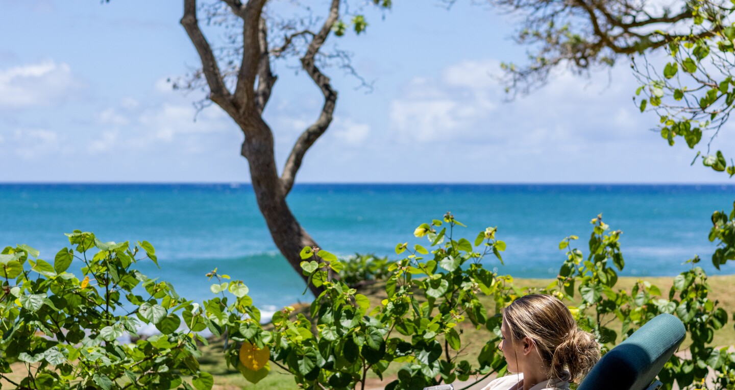 Woman on a lounge chair looking at the ocean at Nalu Spa’s outdoor lounge.
