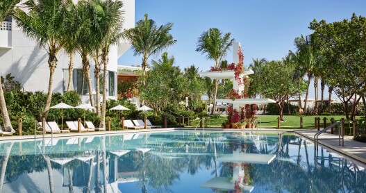 The pool at the Miami Beach EDITION is surrounded by palm tress.