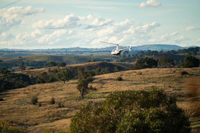 A helicopter flying over brown hillsides