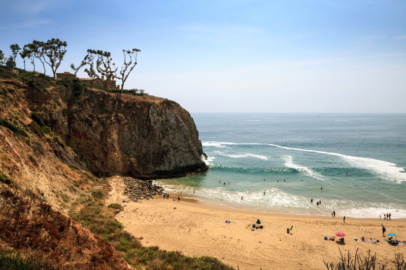 View of people in the water off a golden stretch of sand