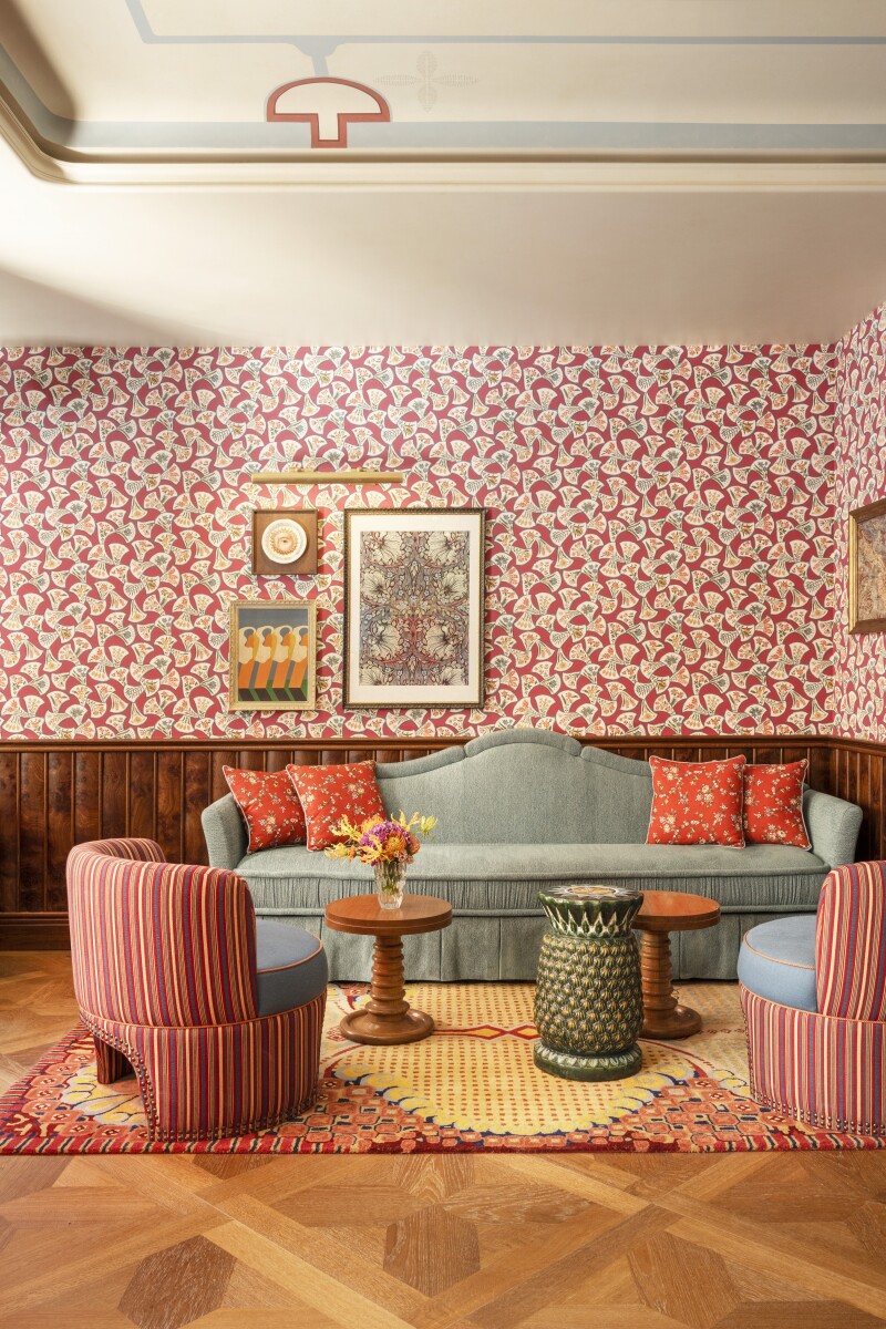 This room at Le Grand Mazarin features striped chairs, patterned wallpaper, and wooden floors.