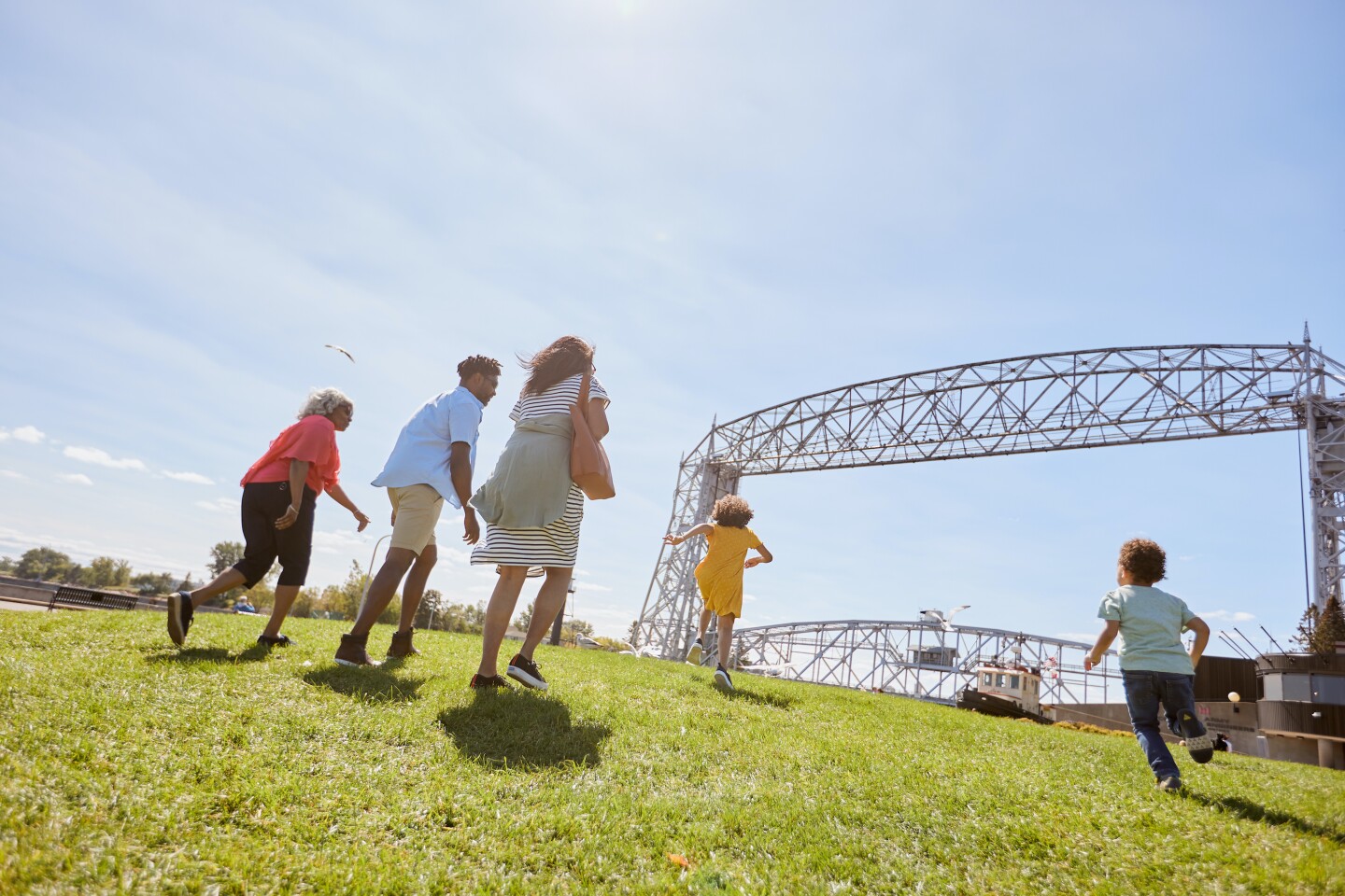 A photo from a low angle of kids and adults running towards the lift bridge in Duluth, Minnesota.
