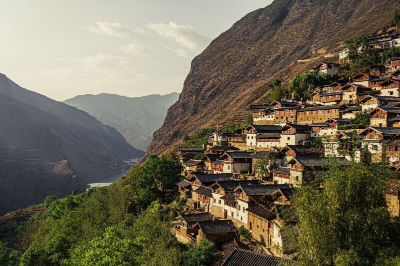 Tiers of houses set into a mountain and looking out over other mountains in Yunnan, Tea Horse Road