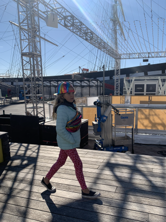 Maya struts through New York City with a holographic cap and matching bag.