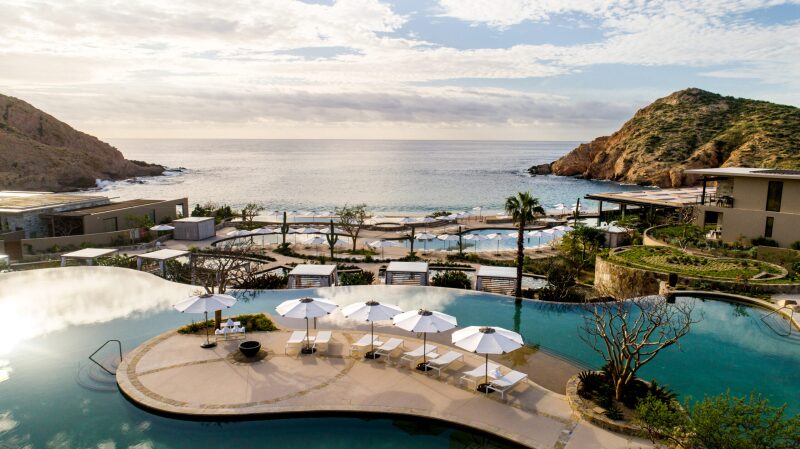 Montage Los Cabos is brimming with oval infinity pools, and outdoor seating. The resort is right on the ocean. Cacti and palm trees fill the resort.