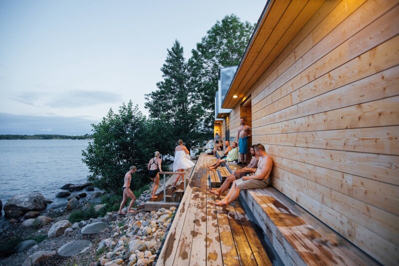People cooling off outside of one of Helsinki’s Finnish saunas near a lake.