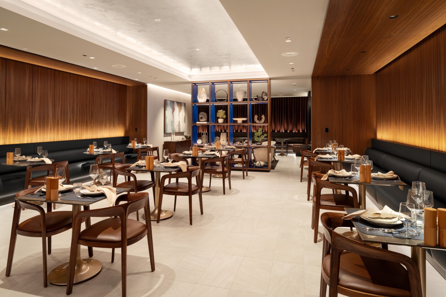 The dining room at O'Hare's newly reopened United Polaris Lounge with wooden midcentury-style chairs, black banquettes, and neutral decor and art