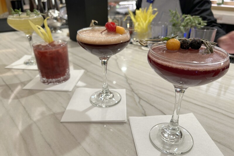four different cocktails in various glasses on a white marble bar