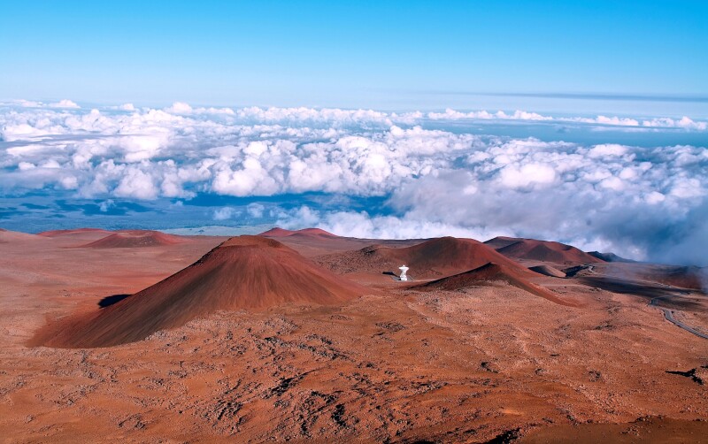 Red volcanic craters level with the clouds and a blue sky