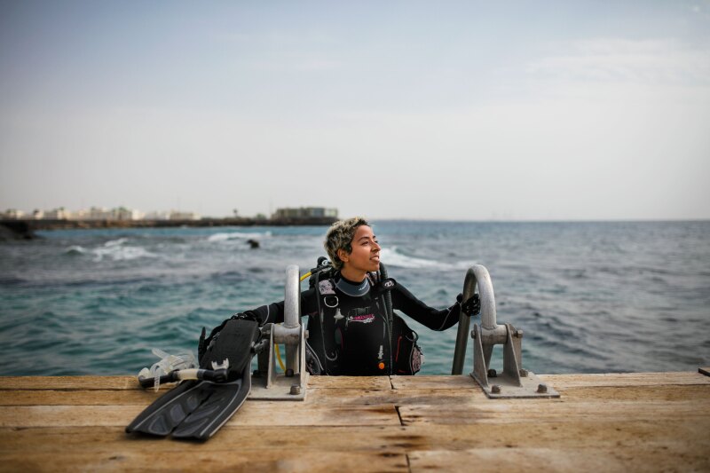 A diver emerges from the water in scuba gear.