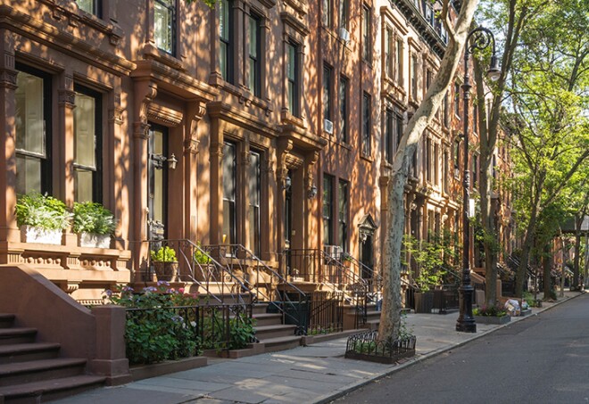Tree-lined street with attractive brownstone buildings in affluent residential neighborhood in Brooklyn Heights, New York.