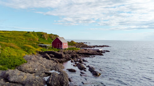 red cabin overlooking the water with no one around