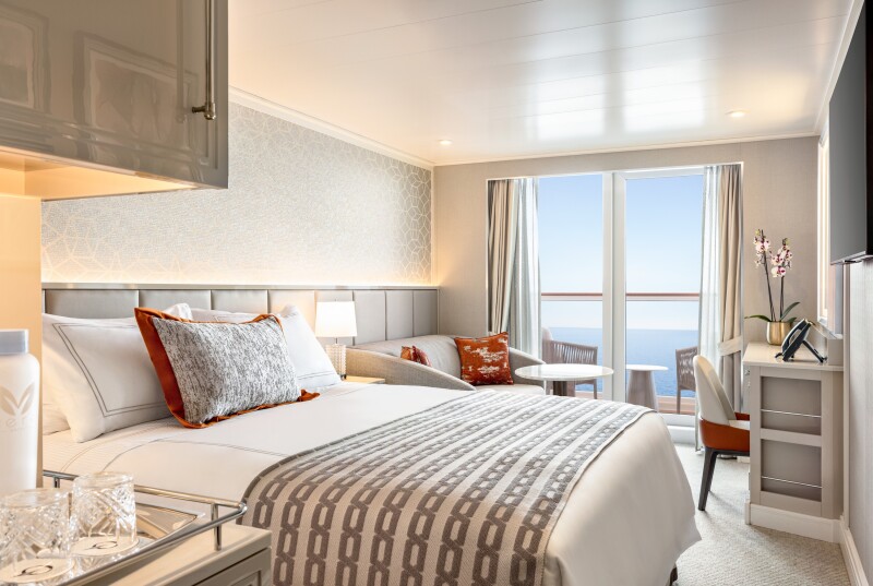 A white veranda stateroom, with one large bed, love seat and coffee table, and balcony