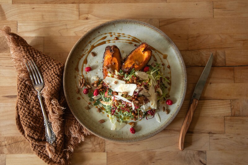 Overhead view of sorghum salad, with roasted squash on wooden table
