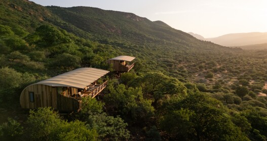 The exterior of a cliffside suite at Few & Far Luvhondo with a curving roof and mountain views