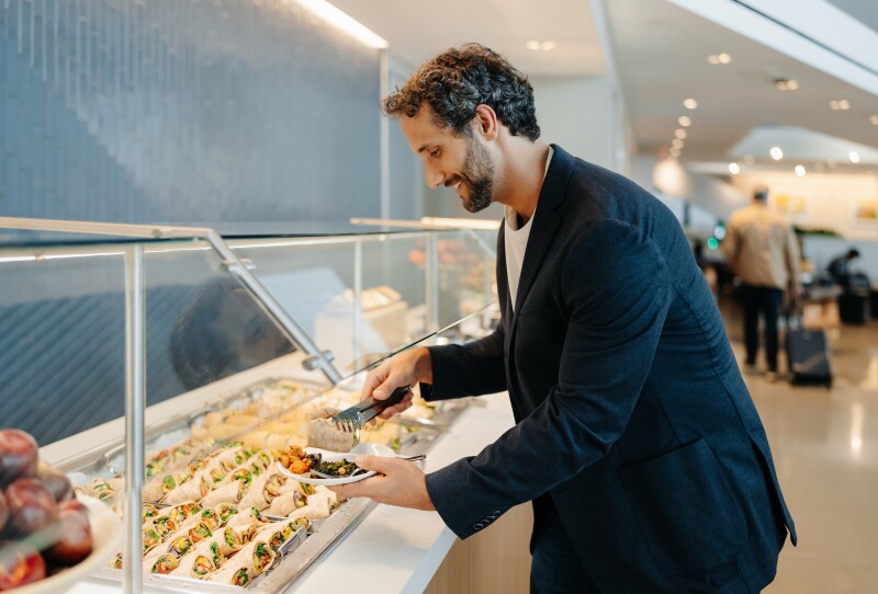 Man serving himself food at the buffet at the United lounge in Newark airport