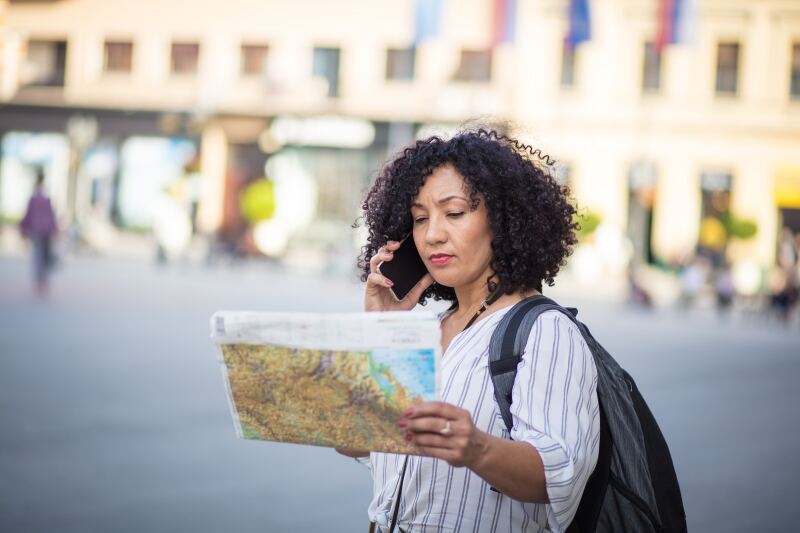 A person speaking on phone while reading paper map