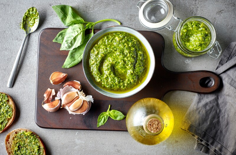 Pesto, which originates from Genoa, Italy, traditionally consists of crushed garlic, pine nuts, coarse salt, basil leaves, and hard cheese—all blended with olive oil.
