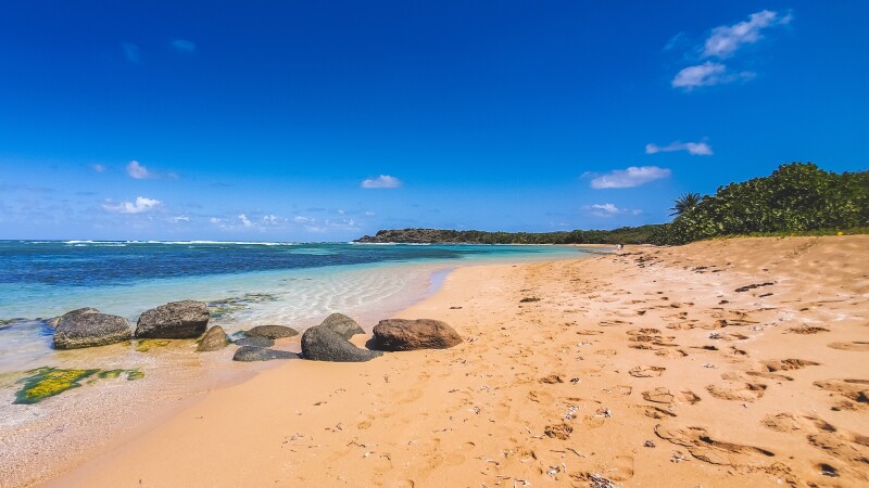 A few rocks on beach with footprints