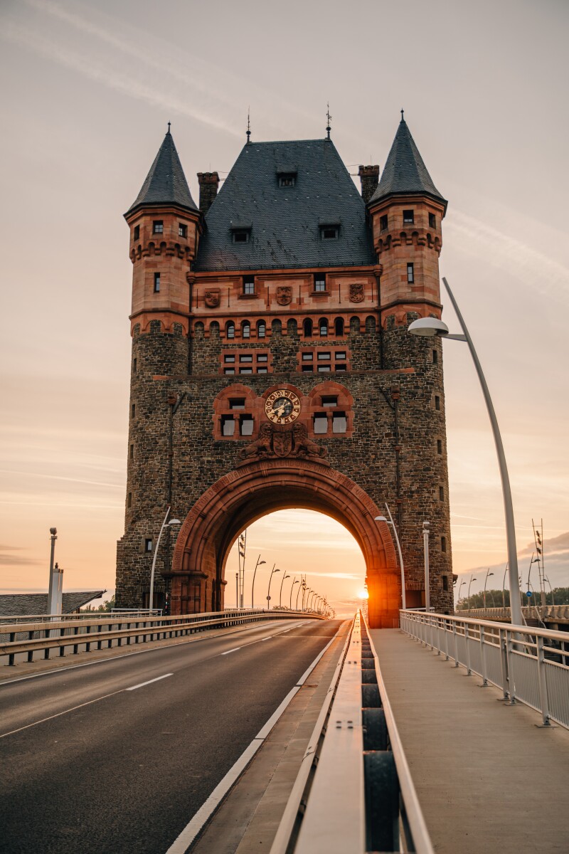 A photograph of the sun setting through the archway of the Nibelung Tower in Worms, Germany