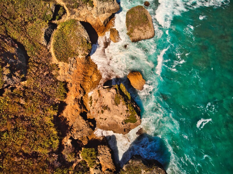 Aerial view of rocky Aguadilla Survival Beach, with green sea at right