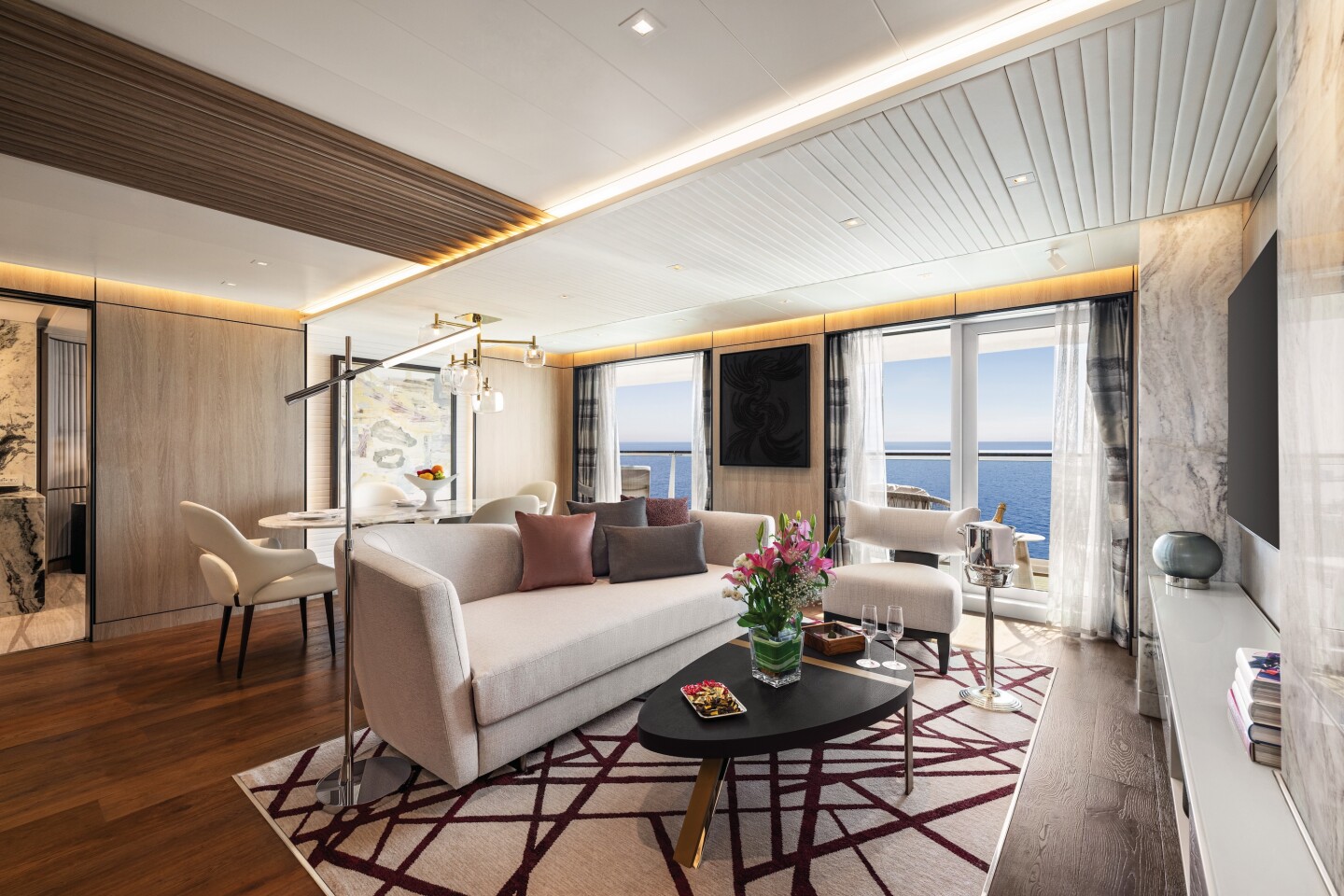 Rendering of beige-and-brown living room in a suite on Oceania's forthcoming 'Allura' cruise ship with a sofa, a coffee table, a small table, and a balcony