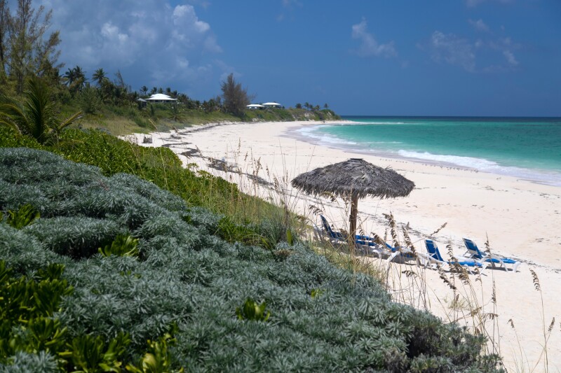 Beach lounge chairs and a standing umbrella by the ocean