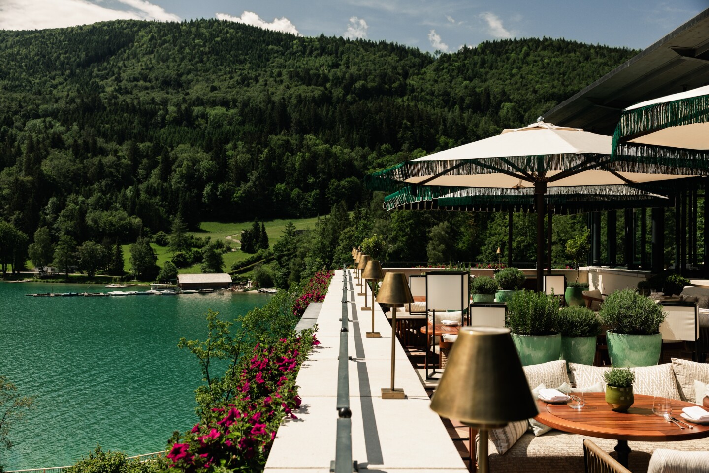 Outdoor terrace, Seeterrasse at Rosewood Schloss Fuschl, with seating, sun umbrellas, and views of Lake Fuschl.