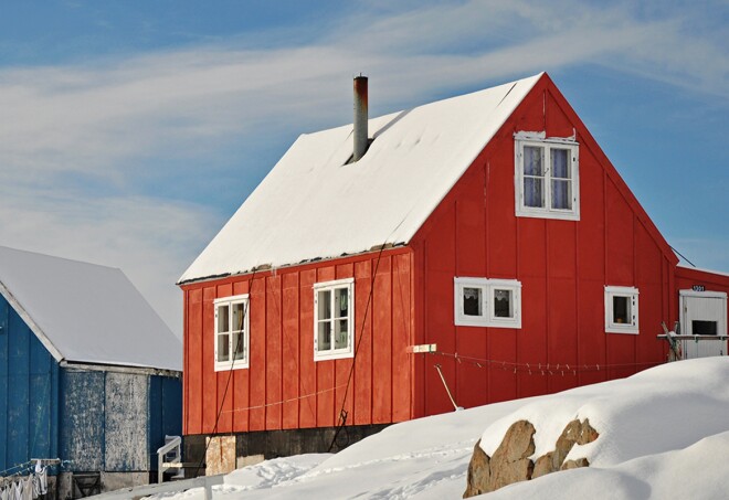 Red and blue house in the snowy Kulusuk village, Greenland