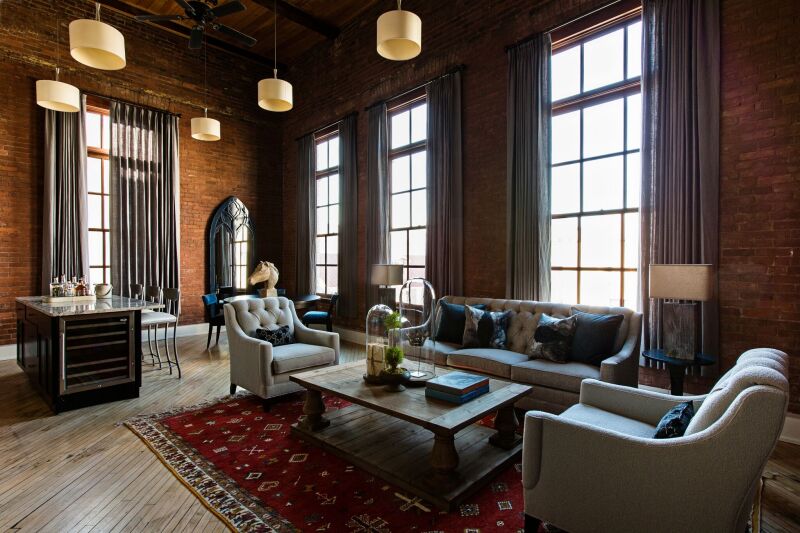 This residential suite at the Restoration Charleston has hardwood floors and large windows with floor to ceiling curtains.