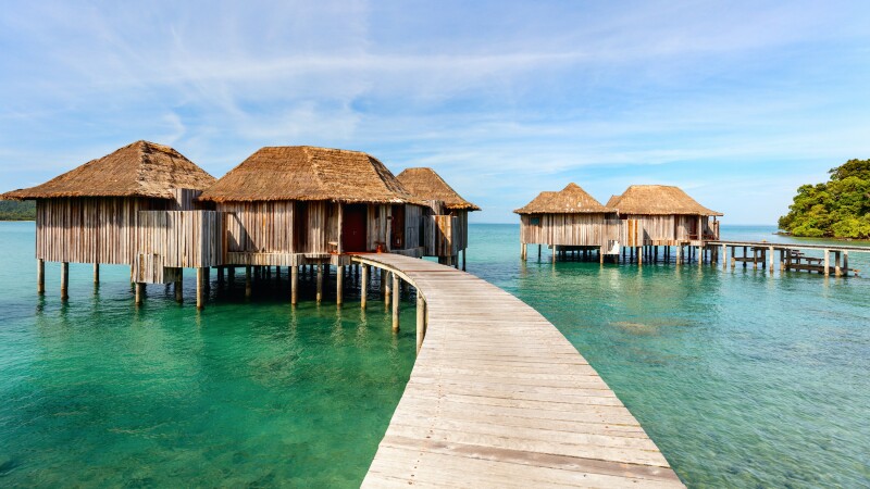 Two wood walkways leading to small clusters of thatched-roof bungalows at Song Saa