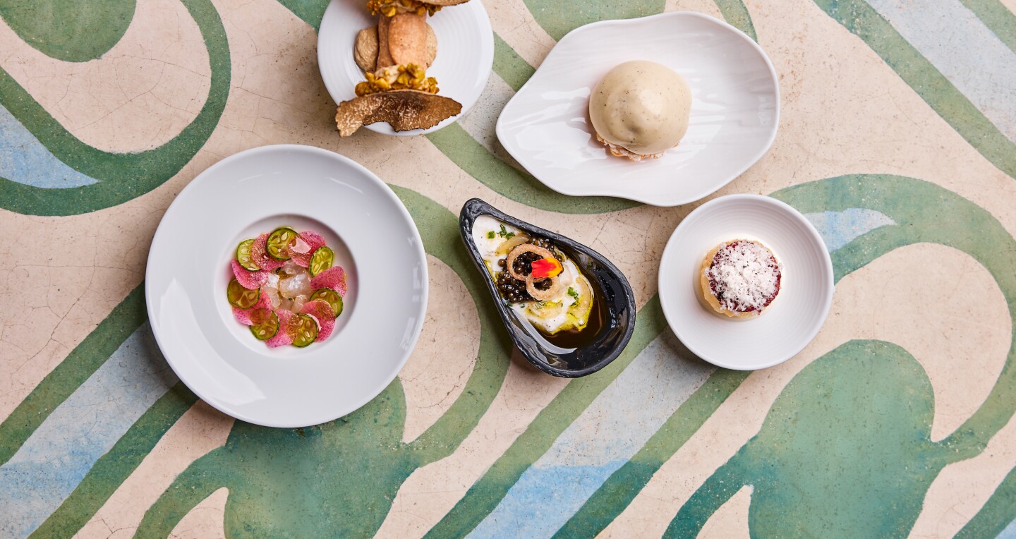 An overhead view of carefully plated dished of food on a patterned table at Masseria restaurant in Washington, DC.