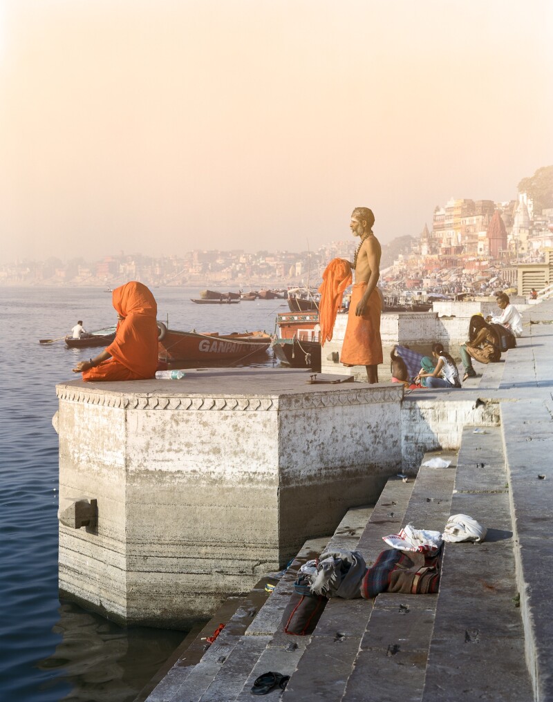 A standing sadhu and a sitting meditator embody the stillness of morning prayer on the ghats along the Ganges River.