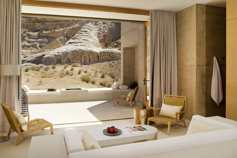 Large white sofa in foreground of beige room with wall open to view of desert
