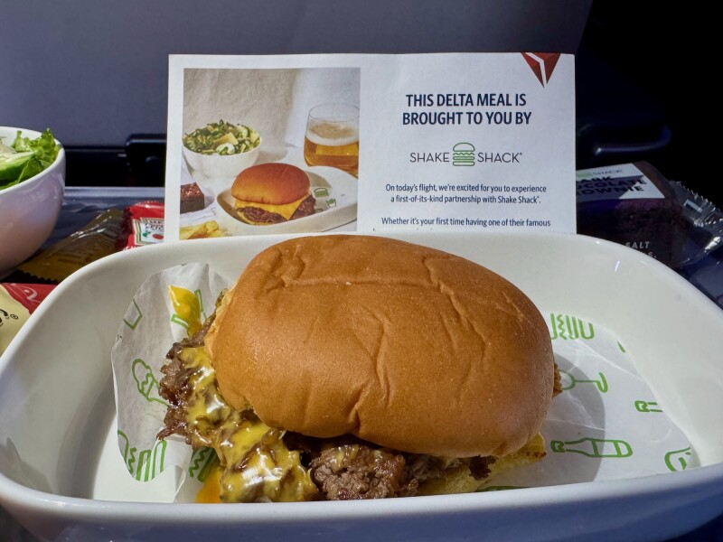 A Shake Shack burger on a white dish, with branded Shake Shack signage