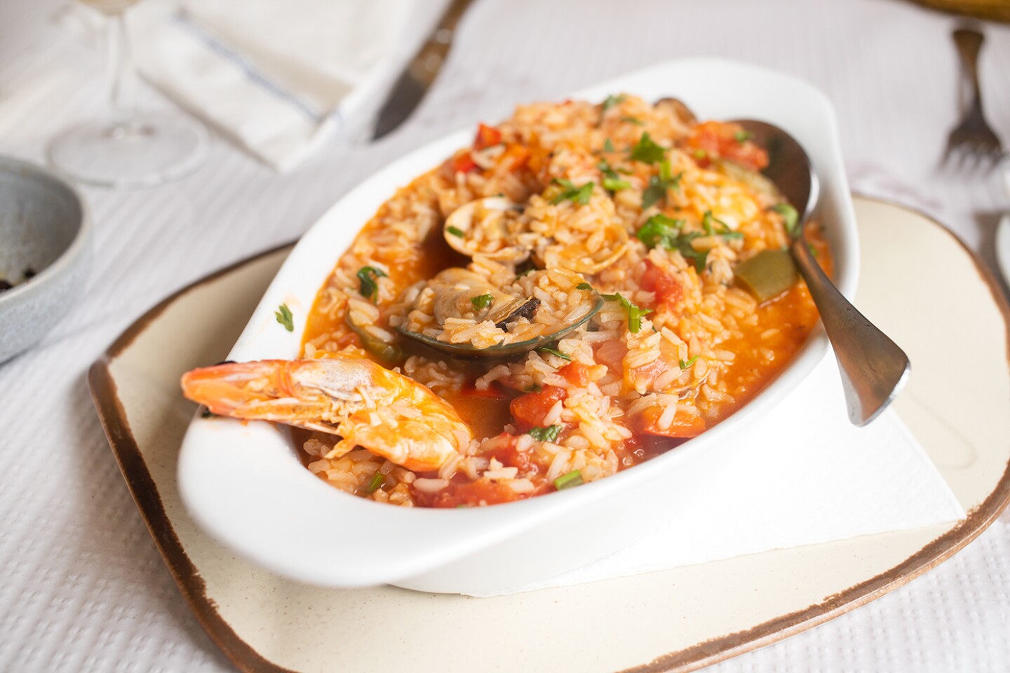 A white dish of soupy rice, with shrimp and clam on top