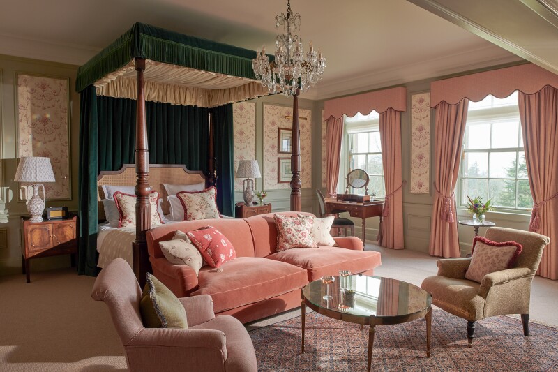 The Royal Lochnagar Suite, with four-poster bed, a large pale salmon sofa at its foot, and pink curtains on large windows