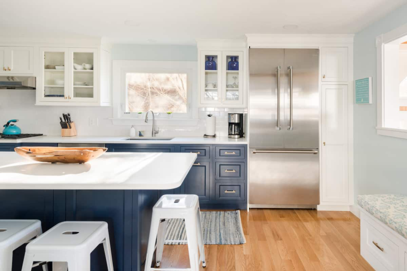 A modern kitchen, with white bar stools around central countertop