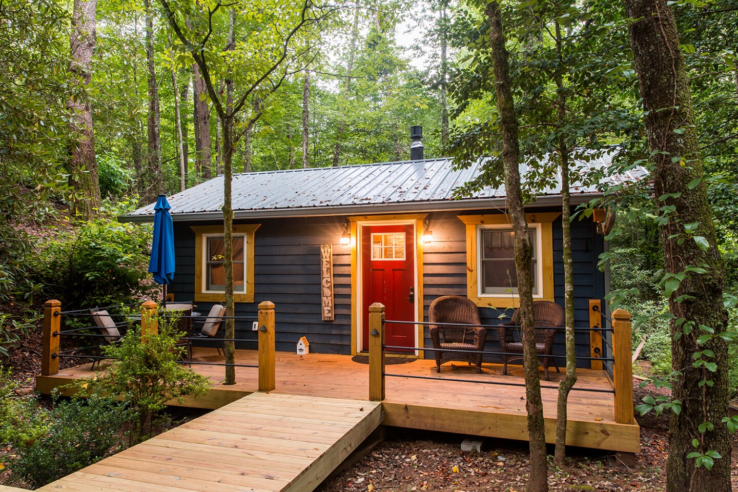 Wooden deck outside front of Georgia cabin, with red door, surrounded by trees