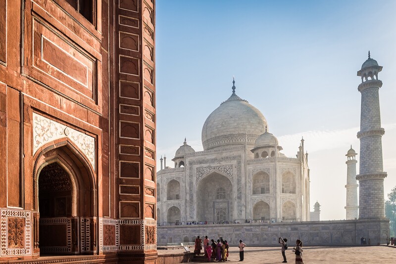 White domed building with a brown building in the foreground, and people outside the brown building taking photos of it