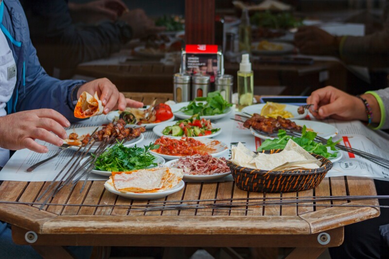 Two people at wooden table eating liver kebab in Beyoglu district