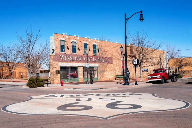 A "Arizona U.S. 66" sign painted on a brick road in front of a brick building in Winslow, Arizona USA
