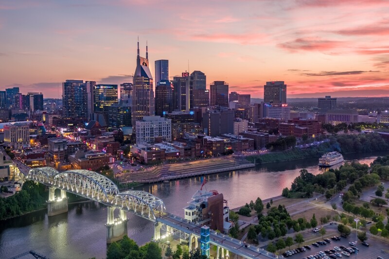 City skyline at sunset, with a river in the middle and a white bridge over it