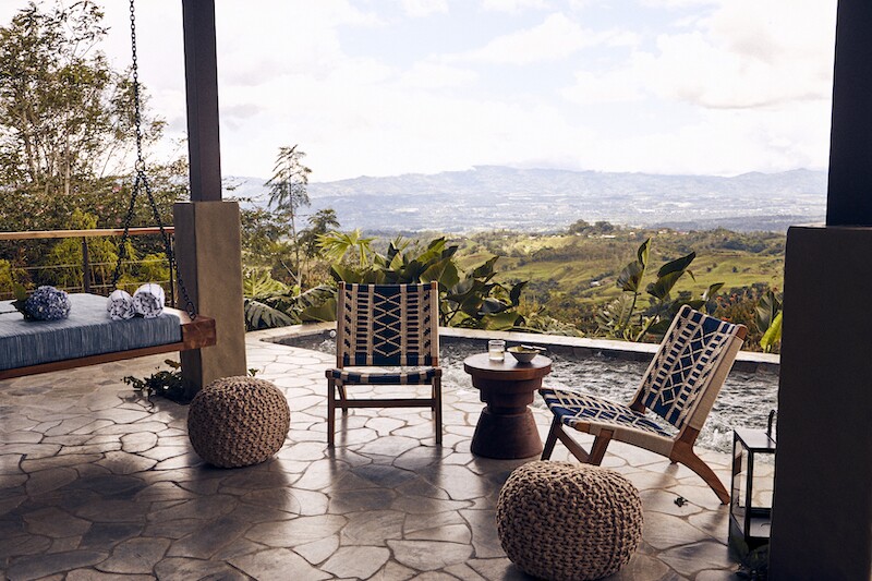 Stone patio with empty chairs and a hanging seat at Hacienda AltaGracia