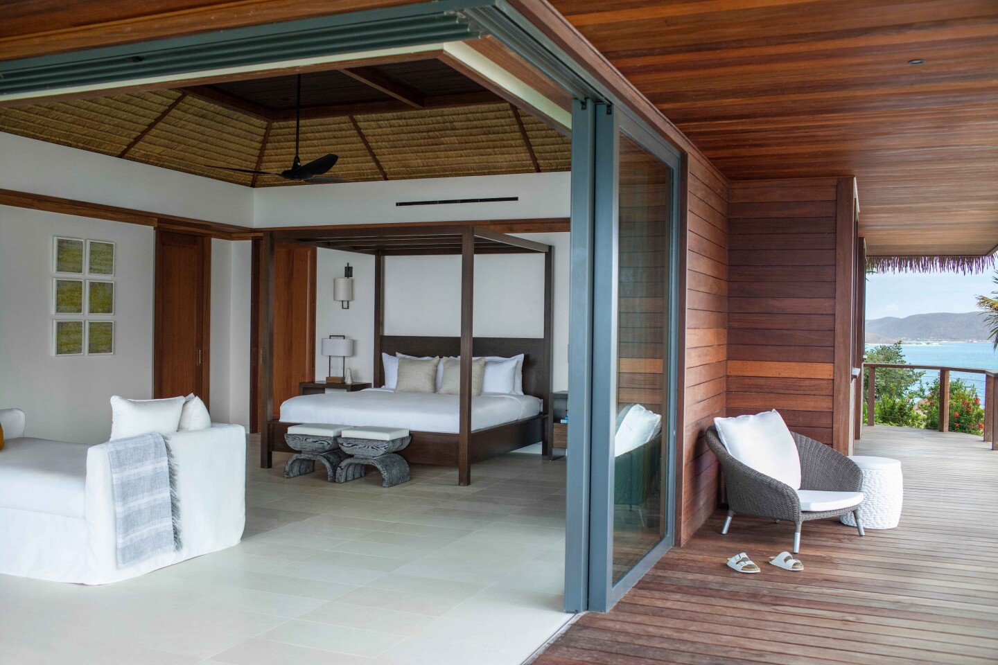 A white hilltop bedroom on Moskito Island, with four-poster bed and open to large wooden veranda