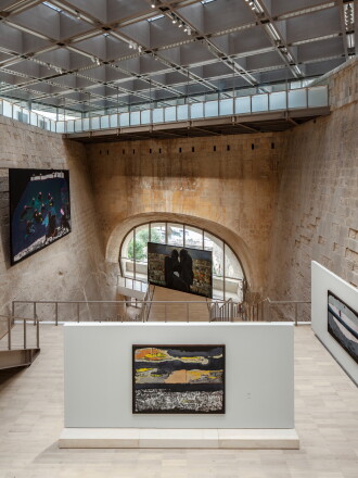 Four art pieces are displayed around a stone chamber with paneled ceiling at MICAS