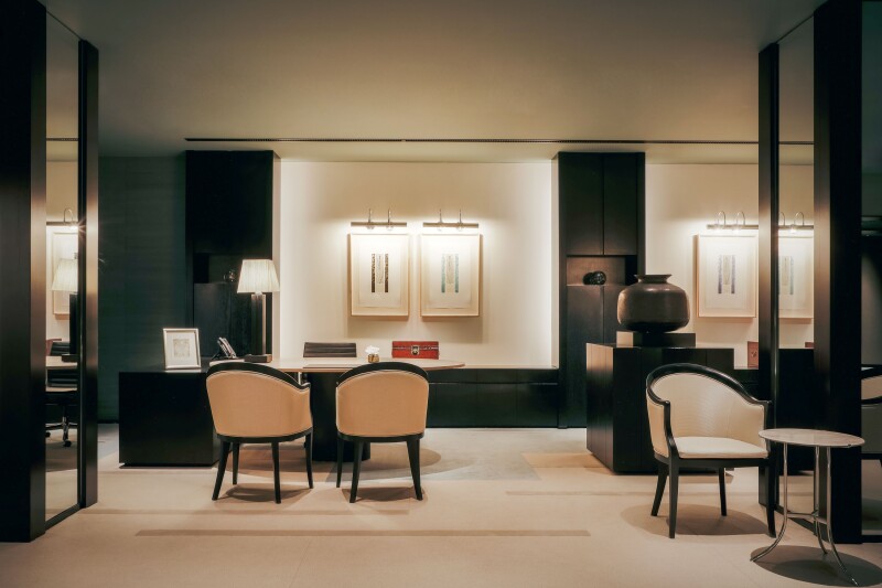 Beige and black front reception, with framed art and wingback chairs