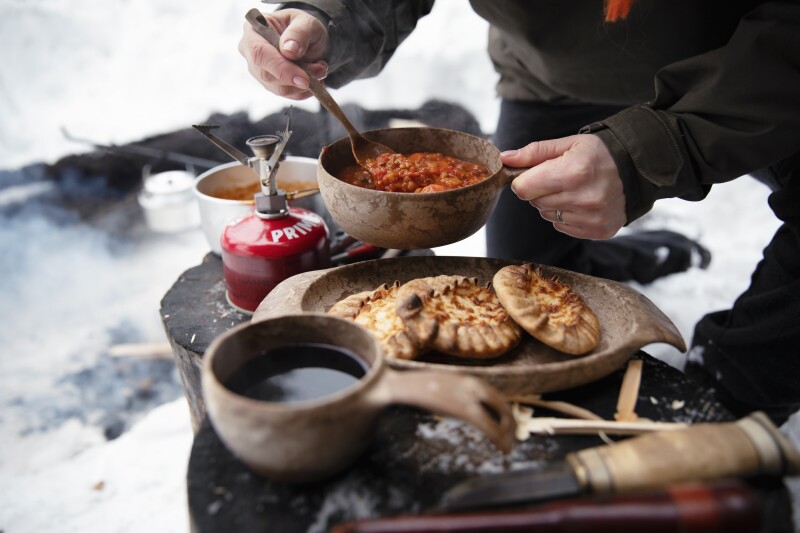 Someone cooking Karelian pasties in a rustic outdoors setting in Finland.