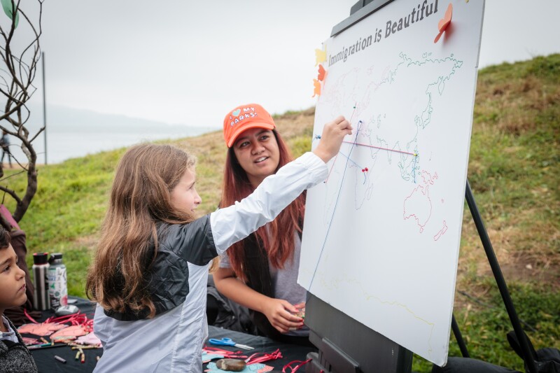 A volunteer from the Parks Conservancy looks on while a child marks her family’s country of origin.