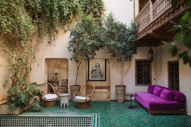 A lounge area at El Fenn in Marrakech with a purple couch and blue tile floors.